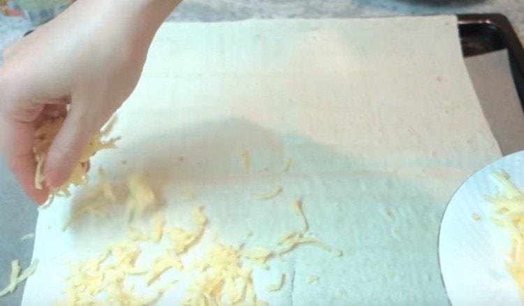 يرش خبز البيتا مع جزء من الجبن المبشور.
