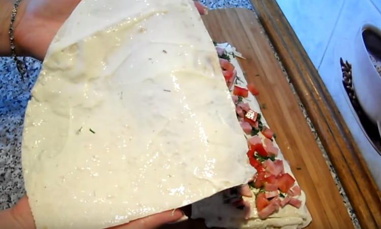 Λιπάνετε το τελευταίο μέρος του ψωμιού πίτας με το υπόλοιπο τυρί και καλύψτε το με το κομμάτι εργασίας.
