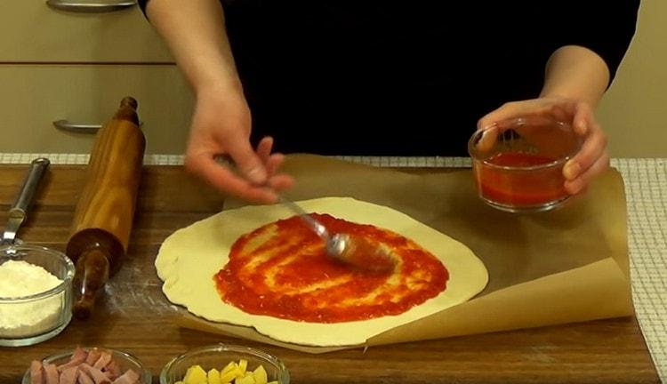 Těsto namažte rajčatovou omáčkou.