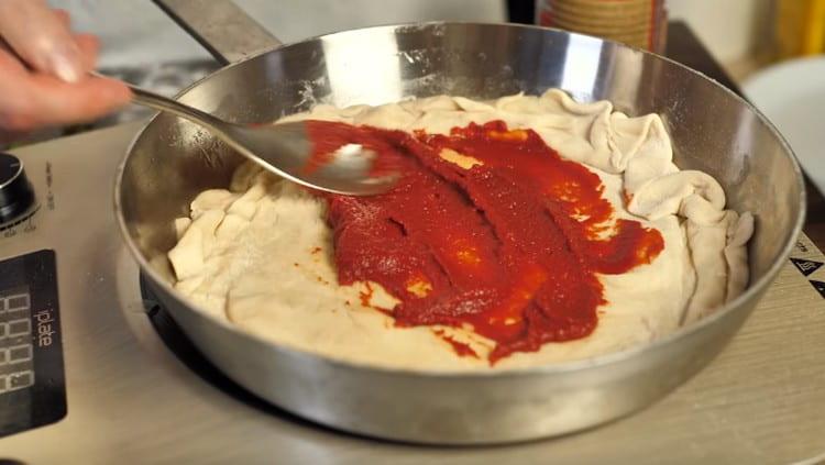 Lubricate ang pundasyon ng aming hinaharap na pizza na may tomato paste.