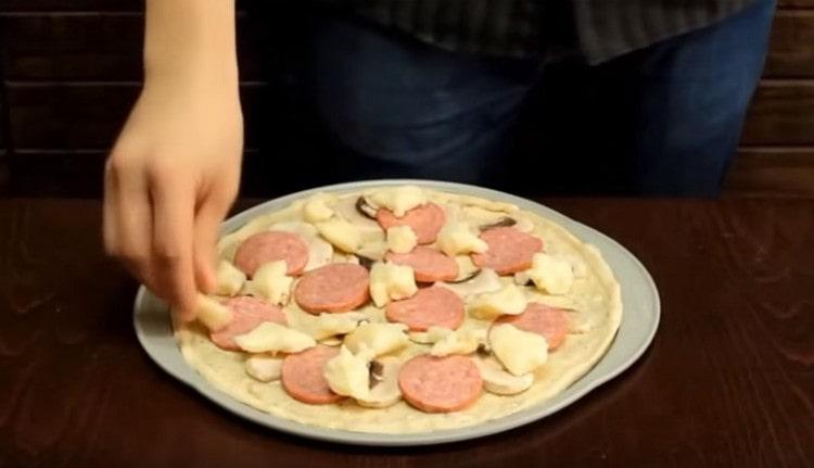 Намажете основата за пица с бял сос, разпределете пълнежа.