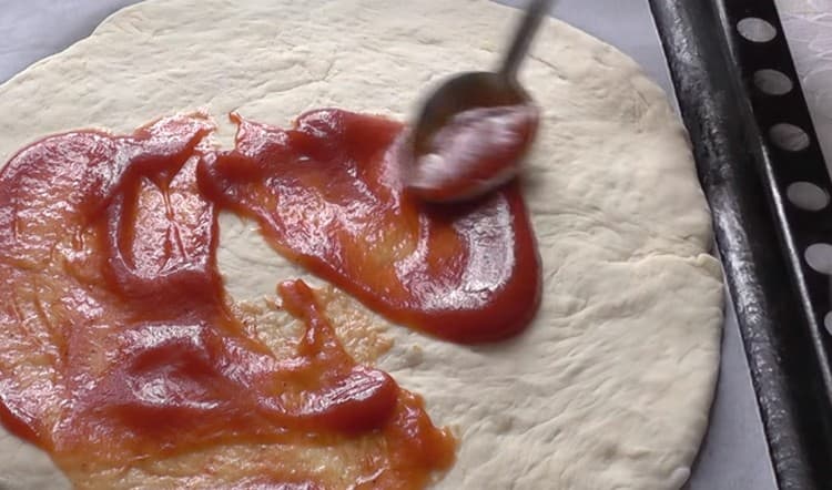 Die Pizza-Basis mit Tomatensauce einfetten.