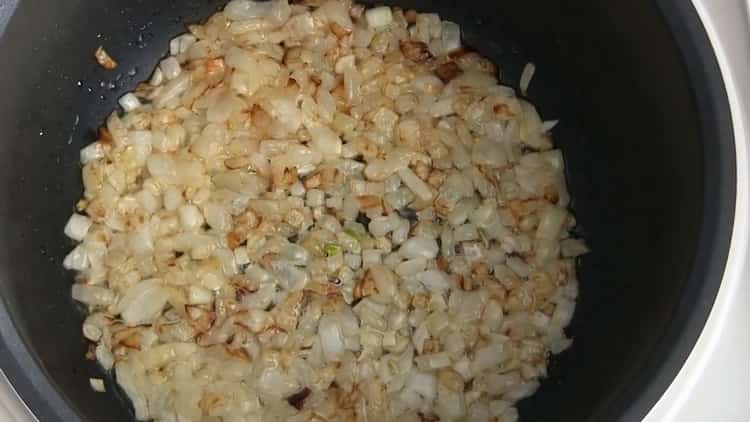 Nach dem Rezept die Zwiebeln braten, um Pilaw in einem langsamen Kocher zu kochen