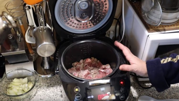 A sertéshúsot eloszlatjuk a multicooker táljában, és megsütjük.