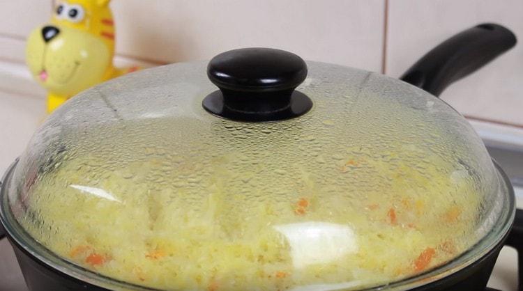 Cucinare pilaf con pollo in una padella sotto il coperchio.