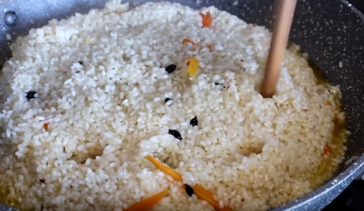 Когато водата частично се изпари, съберете ориза с пързалка и направете дупки в него.