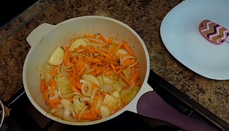 Getrennt gehackte Zwiebeln mit Karotten in einer Pfanne anbraten.