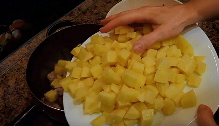 Die Kartoffeln in Würfel schneiden und sofort auf das Fleisch verteilen.