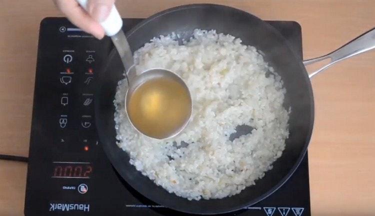 Когато виното се изпари, добавете черпака за супа към ориза.