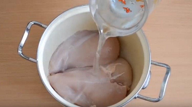 Wir verteilen das Hähnchenfilet in einer Pfanne und füllen es mit Wasser.