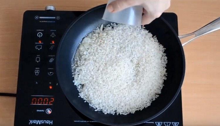Fügen Sie der Zwiebel ein Glas Reis hinzu.