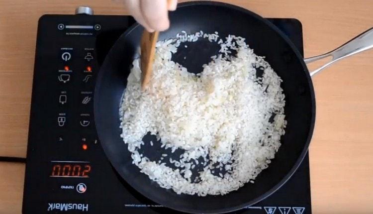 Ψιλοκόβουμε το ρύζι με κρεμμύδια, ανακατεύοντας το.