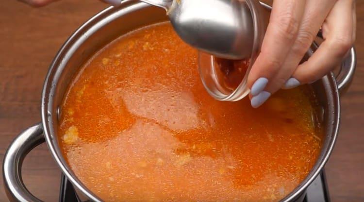Metti la frittura nella zuppa e aggiungi anche un cucchiaio di adjika.