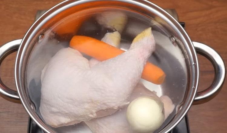 Gießen Sie Wasser in die Pfanne, legen Sie Hähnchenschenkel sowie ganze Zwiebeln und Karotten hinein.