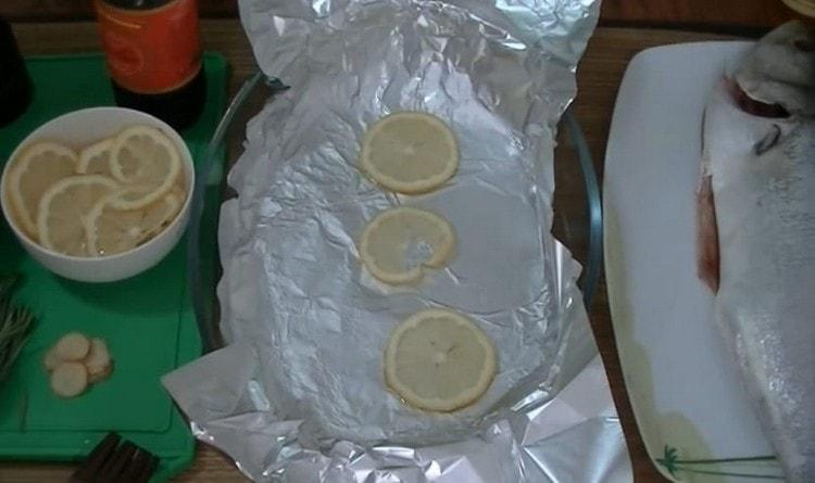 Καλύψτε το ταψί με φύλλο αλουμινίου, λιπάνετε με φυτικό λάδι και απλώστε μερικές φέτες λεμονιού.
