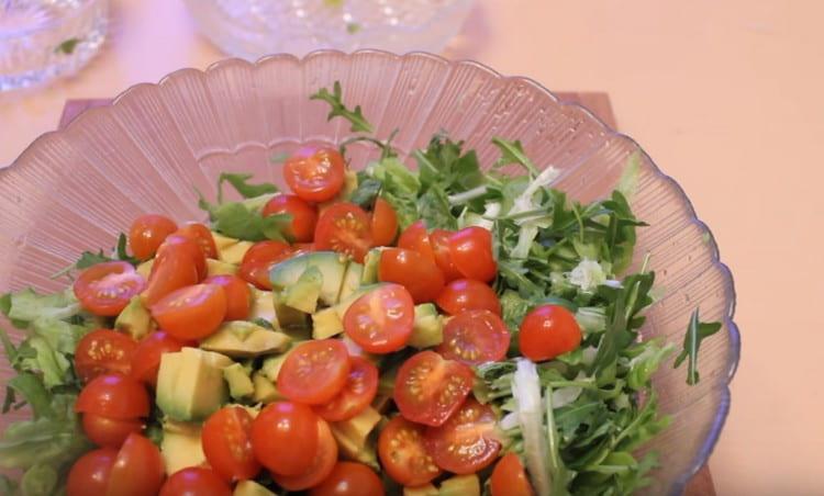Βάλτε τις ψιλοκομμένες ντομάτες και το αβοκάντο σε ένα μεγάλο πιάτο με ρόκα.