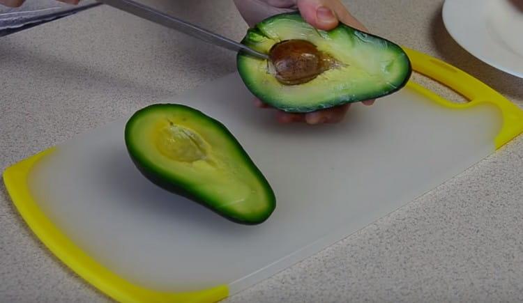 Taglia l'avocado a metà ed elimina una pietra.
