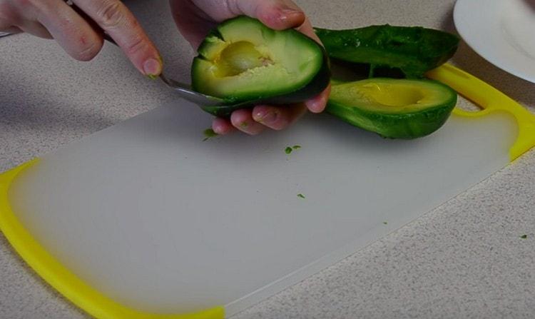 Usando un cucchiaino, rimuovi la polpa dell'avocado dalla buccia.