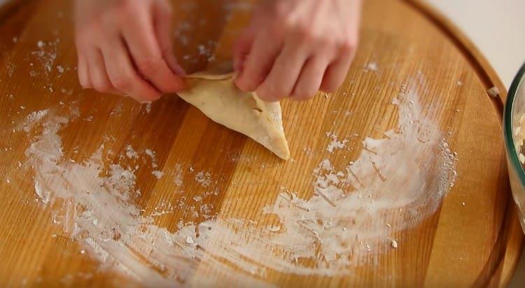 tegye a tölteléket a kapott sütemény közepére, és gyűjtsük össze a tészta széleit háromszög formájában.