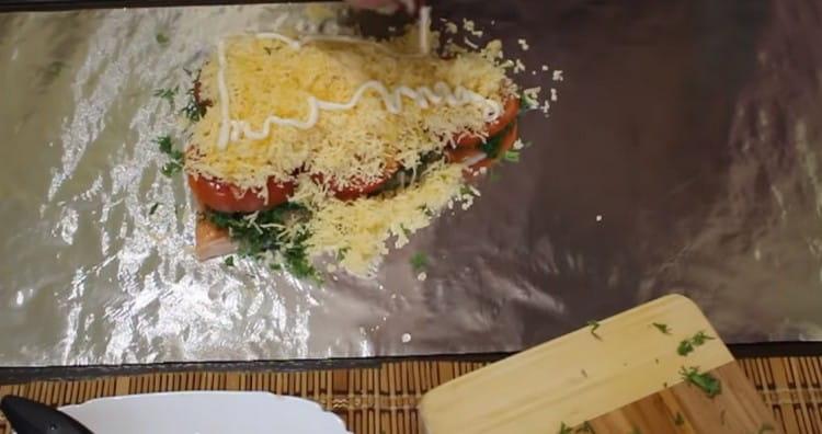 Ψεκάστε ελαφρά τα ψάρια κάτω από το τυρί με φυτικό έλαιο και κάντε ένα δίχτυ μαγιονέζας πάνω σε αυτό.