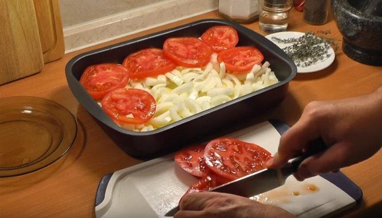 Ant svogūnų sluoksnio paskirstykite supjaustytus pomidorus.