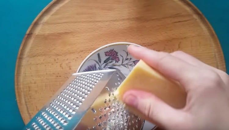 Su una grattugia fine strofiniamo il formaggio a pasta dura.