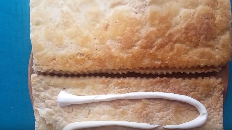 Grasa ang inihurnong puff pastry na may mayonesa.