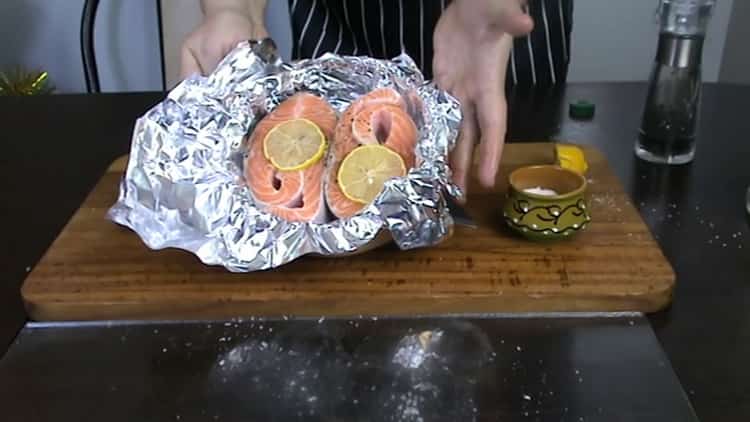 Metti il ​​limone sul pesce per cuocere la trota nel forno.