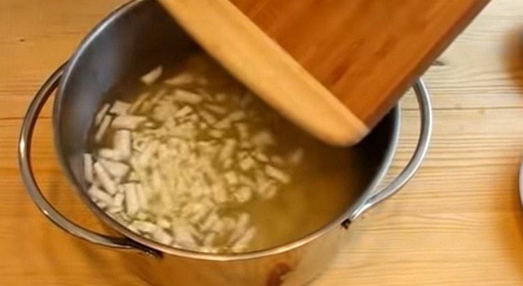 Do vývaru vložte brambory a nakrájenou cibuli.
