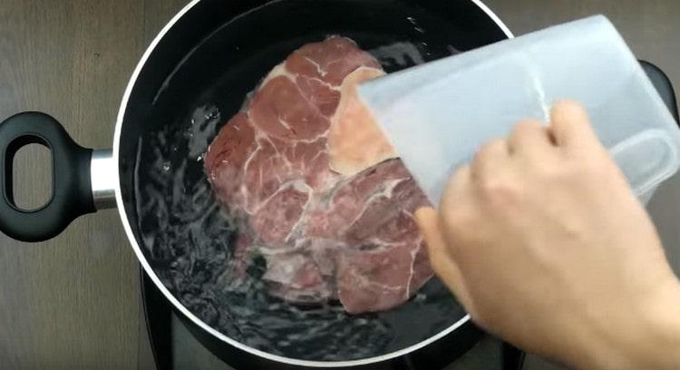 Сложете говеждото месо в тиган, напълнете го с вода и поставете да готви.