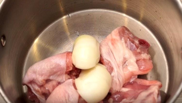 A csirkehúst eloszlatjuk a serpenyőbe, hozzáadjuk a hagymát, felére vágva.