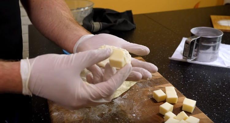 Във всяко парче тесто слагаме кубче сирене.
