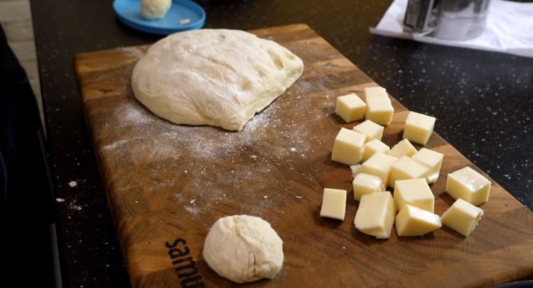 A sajtot nagy kockákra vágják, és a tésztát a sajtdaraboknak megfelelő adagokra osztják.