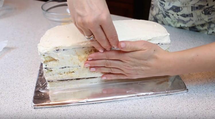 Nachdem Sie die Ränder des Kuchens mit der restlichen Creme eingefettet haben, bestreuen Sie sie mit Kekskrümeln.