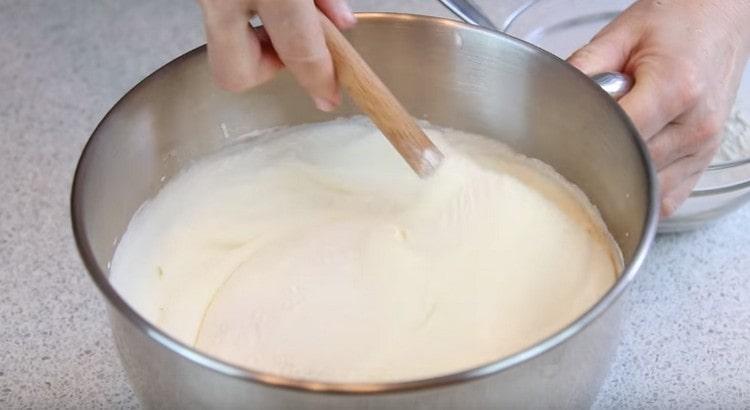Introduciamo farina con amido nella massa di uova, mescolando delicatamente tutto con una spatola dal basso verso l'alto.