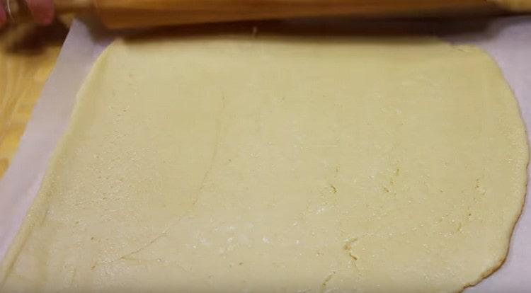 Разточваме по-голямата част от тестото директно върху пергамента до размера на листа за печене.