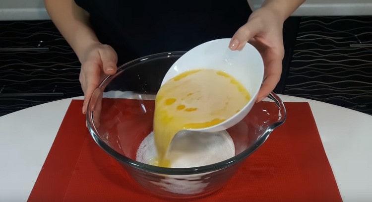 Изсипете захарта в купа и я напълнете с разтопено и леко охладено масло.