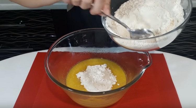 Nachdem wir Mehl mit Backpulver gemischt haben, beginnen wir, es den flüssigen Bestandteilen zuzuführen.