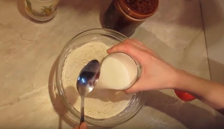 Aggiungi il latte alla farina e inizia a mescolare la massa con un cucchiaio.