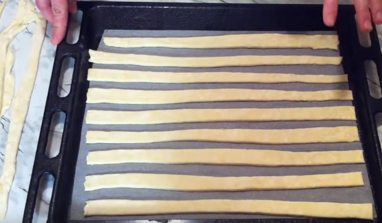 Разстиламе лентички тесто върху лист за печене, покрит с пергамент.