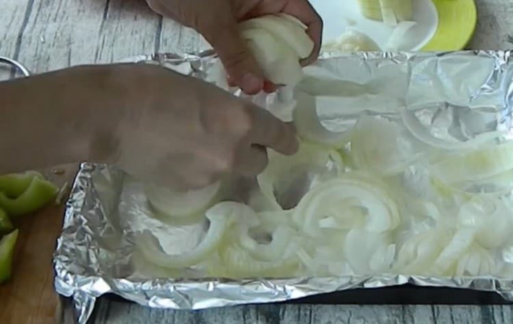 تُوزّع طبقة من البصل على ورقة الخبز المغطاة بورق.