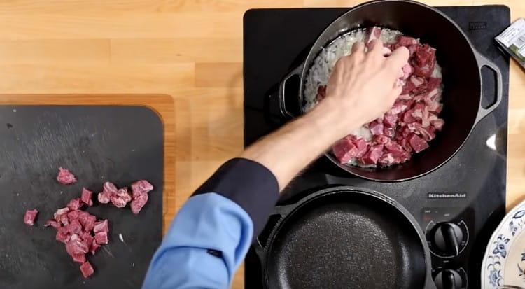 Vágja a húst apróra és darabolja a hagymát az üstbe.