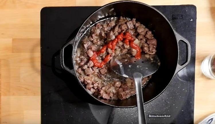 Добавете доматеното пюре към месото с лука.
