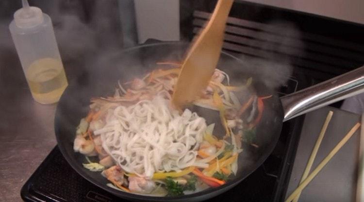 Διανέμουμε τα noodles στο τηγάνι στο κοτόπουλο και τα λαχανικά, ανακατεύουμε.