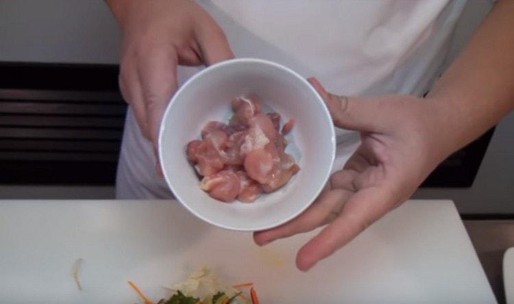 La carne di pollo viene tagliata in piccoli pezzi.