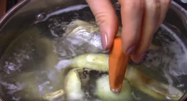 Във врящ бульон добавете черен пипер, лук, моркови.