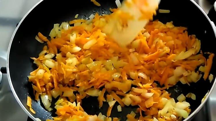 Τηγανίζουμε τα κρεμμύδια με τα καρότα μέχρι να μαγειρευτούν σε μια κατσαρόλα.