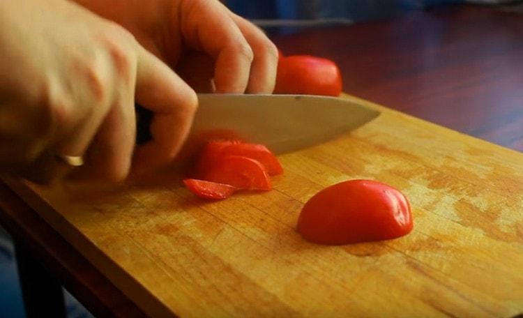 Wir schneiden Tomaten in dünne Halbkreise.
