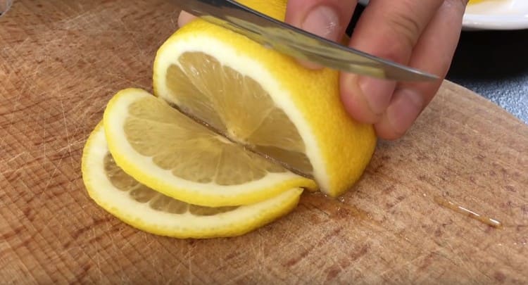 Die Zitrone in dünne Kreise schneiden.