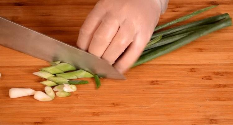 Leikkaa vihreät sipulit vinosti.